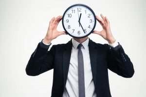 A man holding a clock in front of his face