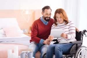 a woman in a wheelchair looking at an ipad with a man