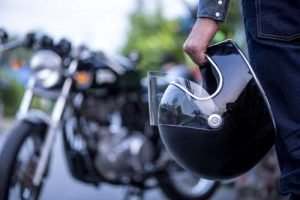 a man holding a helmet in front of a motorcycle