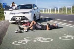 a cyclist laying on the ground after being hit with a car