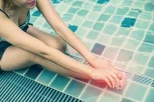 woman holding her toe in a swimming pool