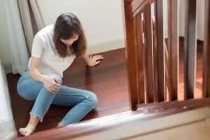 woman holding knee at bottom of stairs