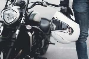 guy in front of motorcycle holding helmet