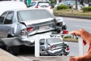 man taking picture of wrecked car