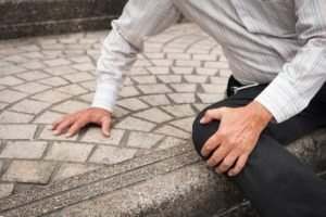 man clutching injured knee