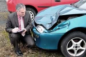 man inspecting damaged vehicle