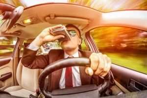 man drinking out of flask while driving