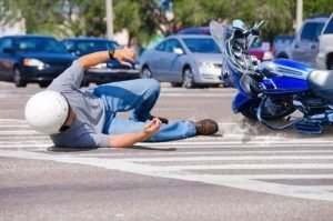 man laying in sidewalk next to motorcycle