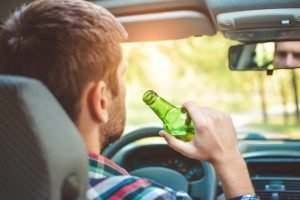 man-drinking-from-beer-bottle-while-driving