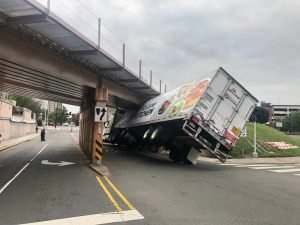 delivery truck wedged under a bridge