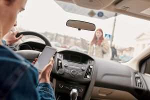 distracted male driver on his phone about to hit a female pedestrian