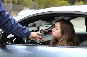 female driver taking a breathalyzer test