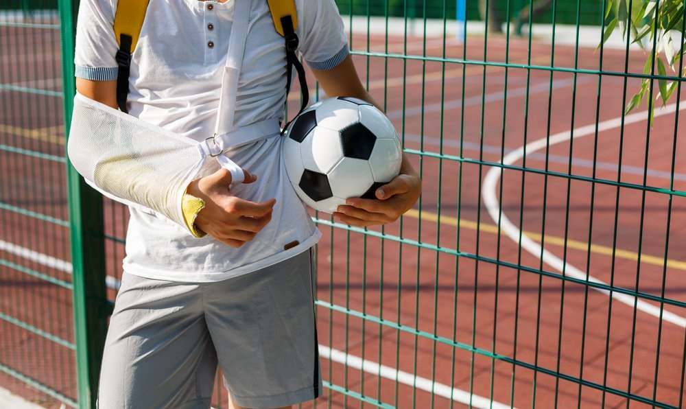 man with a broken arm holding a soccer ball