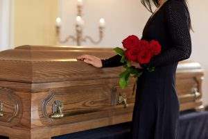 woman holding roses and touching a casket