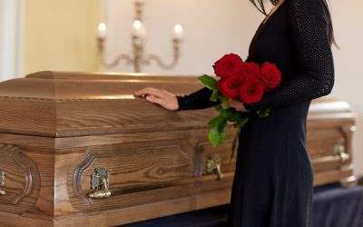 woman holding roses and touching a casket