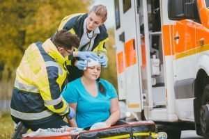 woman getting her head bandaged at an ambulance