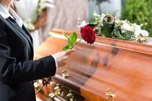 woman putting a rose on a coffin