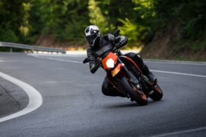 Motorcyclist Riding Orange Motorcycle on Curved Road Outdoors